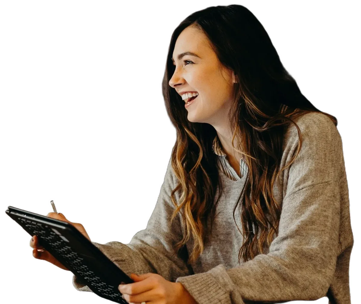 Someone with long dark hair in a gray sweater laughing, holding a tablet and stylus